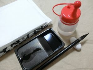 筆と硯と水差しと書き終わった紙